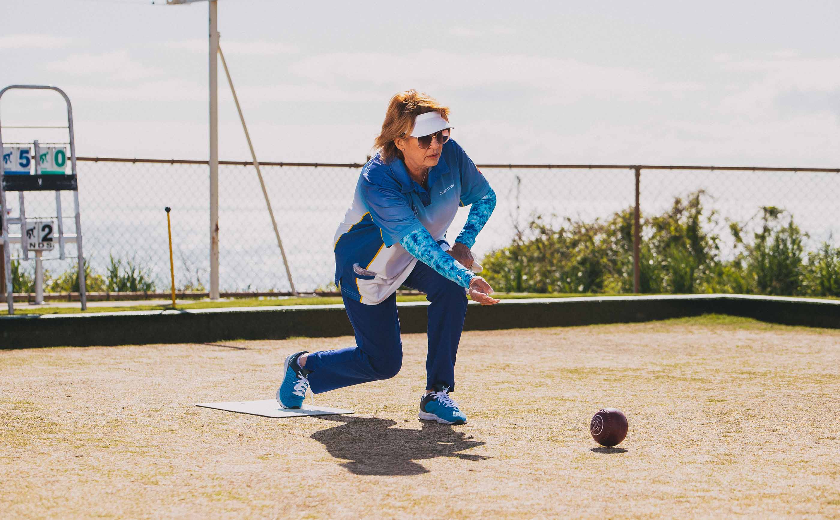Lady playing lawn bowls wearing Coral Crazy Arms sun sleeves