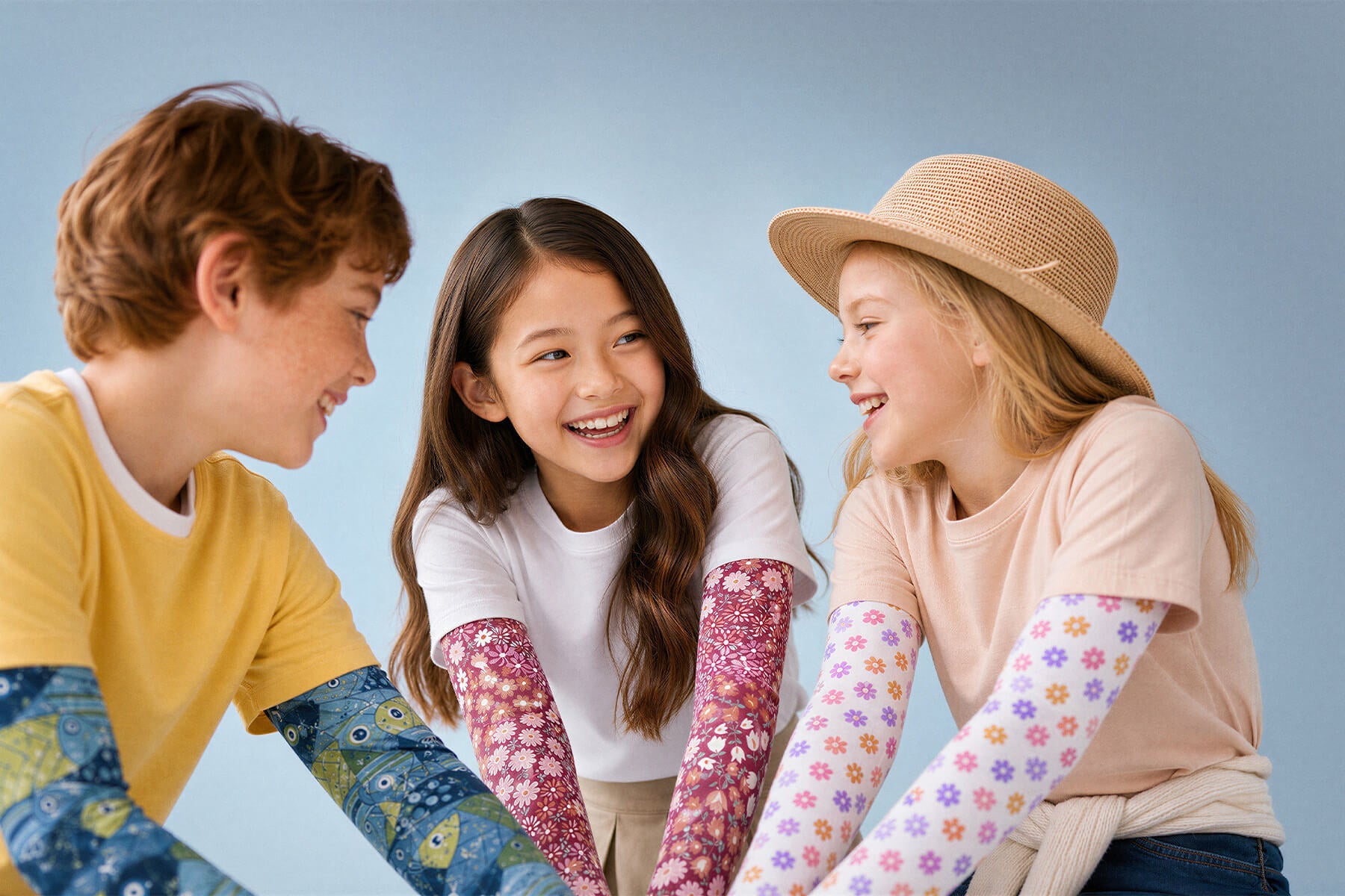 Three girls excitedly jumping over the waves on the shoreline, wearing Crazy Arms sun sleeves