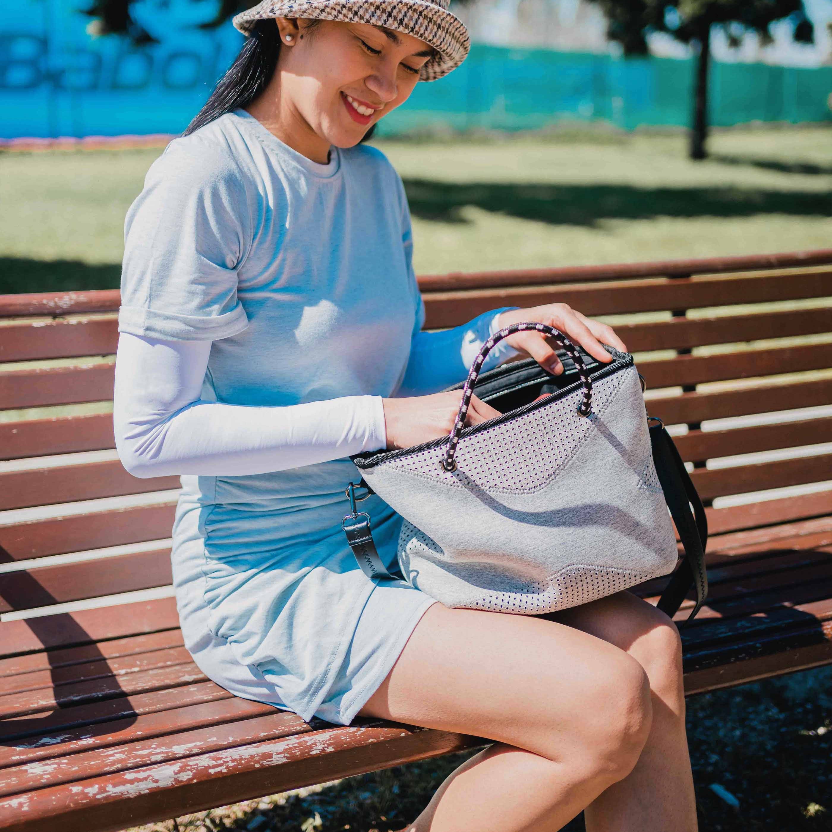 Young woman sitting outside wearing a hat and Crazy Arms 