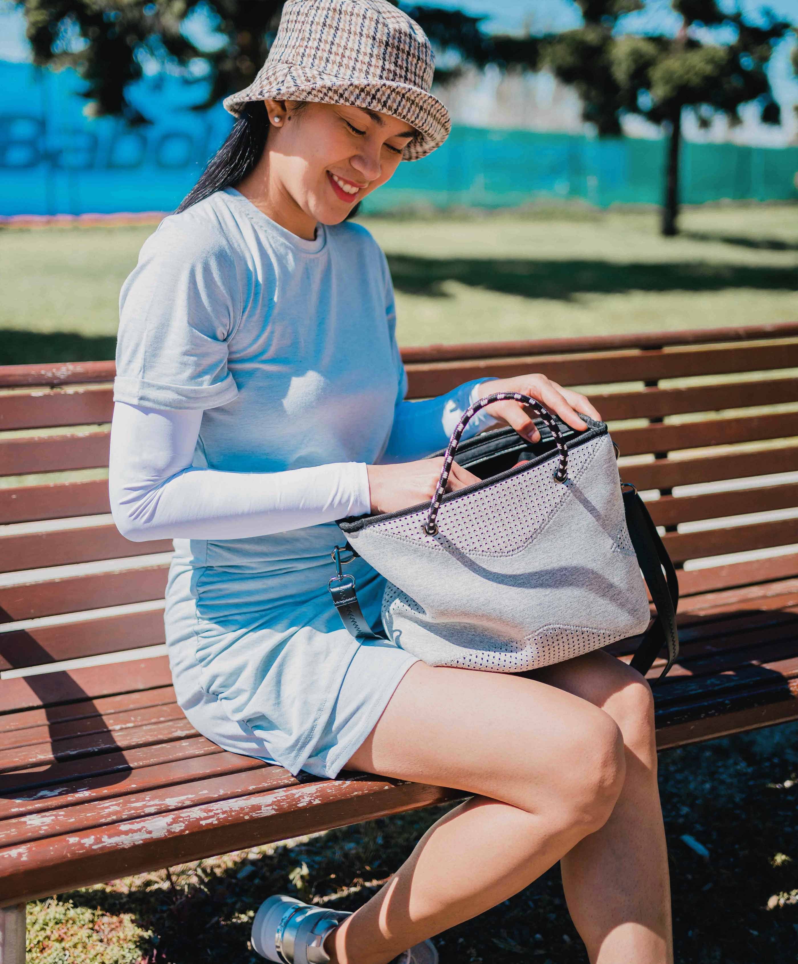 Young woman sitting outside wearing a hat and Crazy Arms 