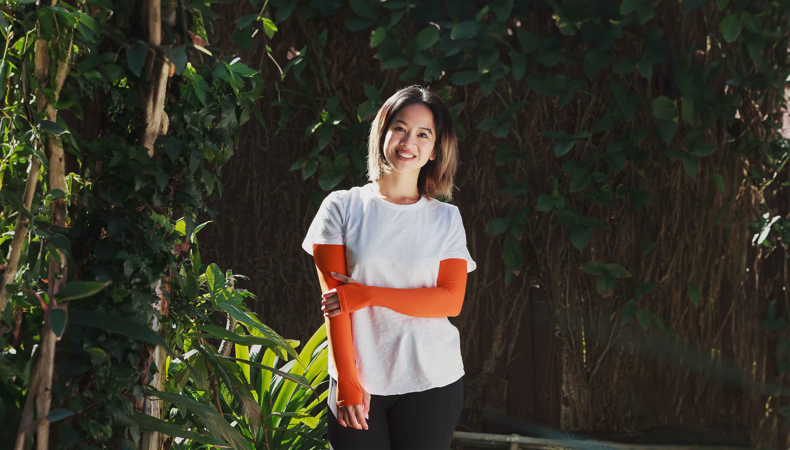 Happy women standing in garden setting, wearing Orange thumbhole Crazy Arms sun sleeves
