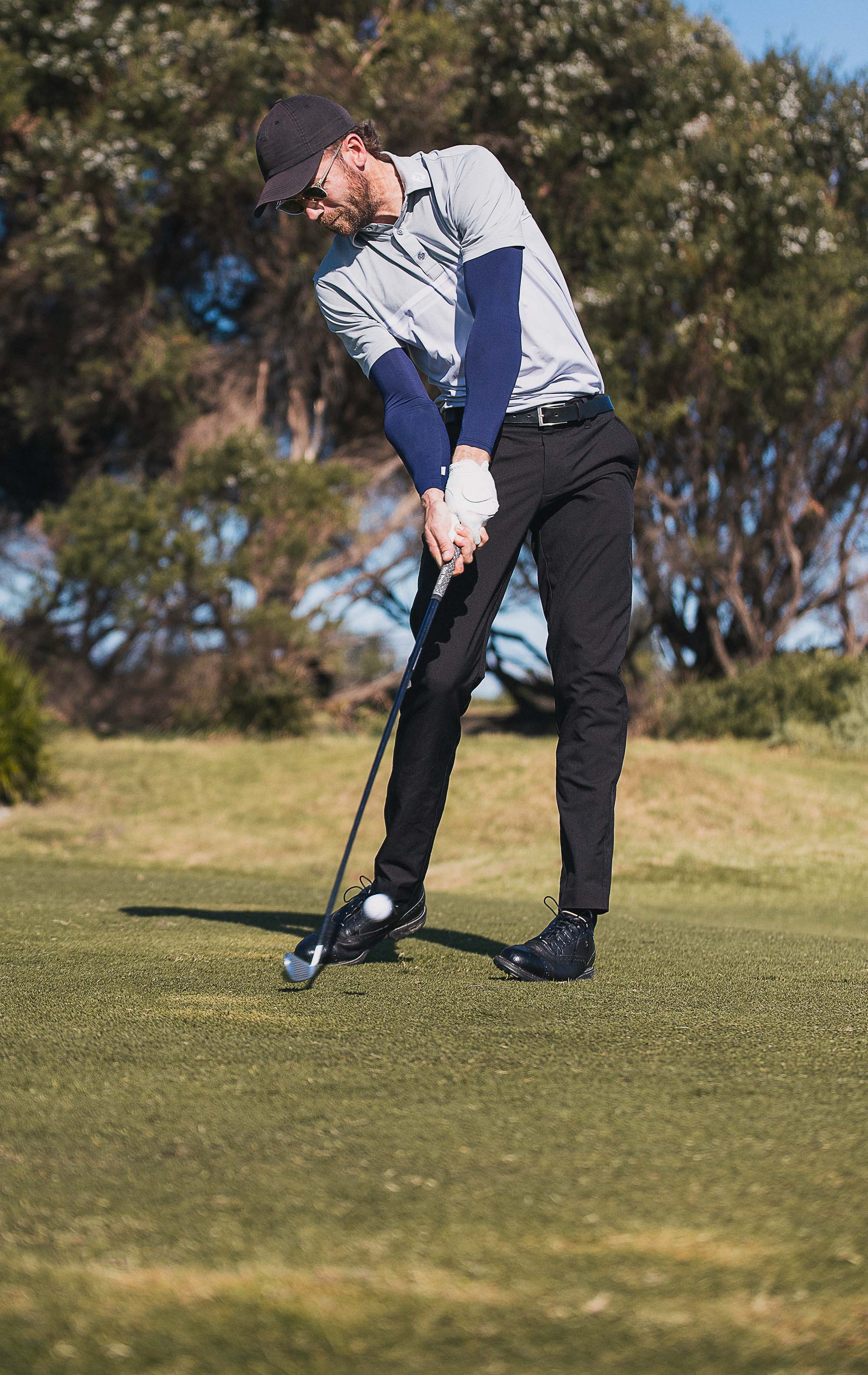 Man wearing navy blue Crazy Arms sun sleeves taking golf swing