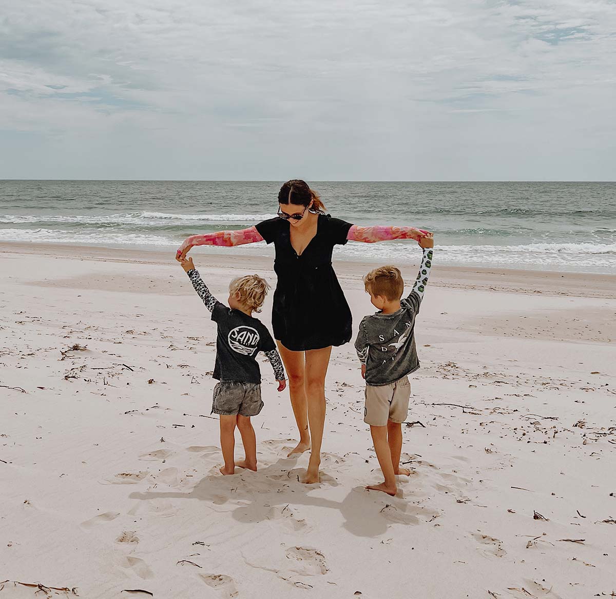 Mum playing with her two suns on the beach, all wearing Crazy Arms sun protective sleeves