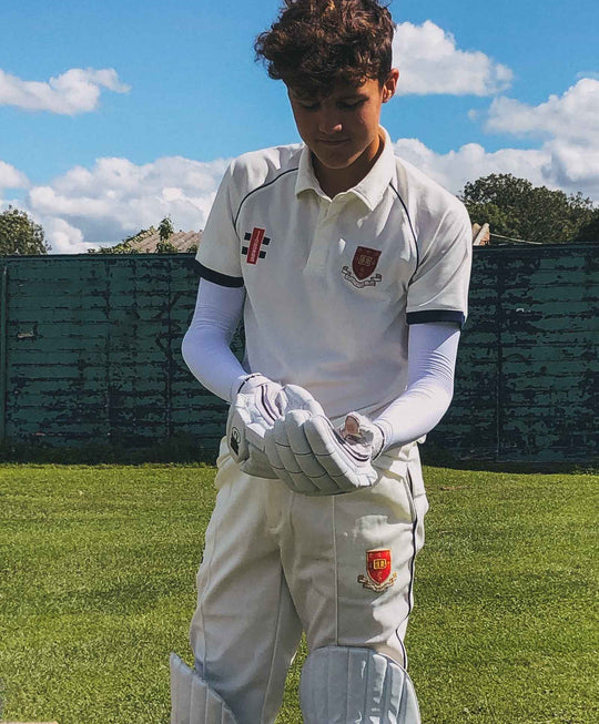 Cricket player putting batting gloves on, whilst wearing Crazy Arms sun protective sleeves